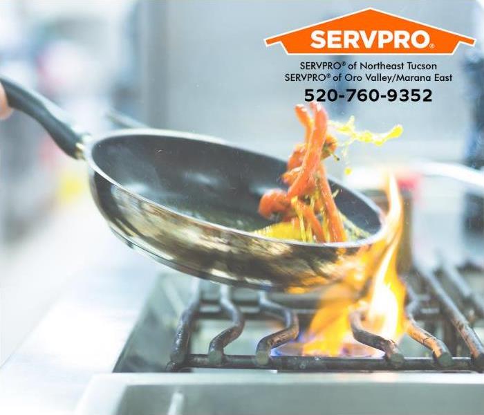 Flames leap from a gas stove burner while a person is cooking with oil in a skillet.