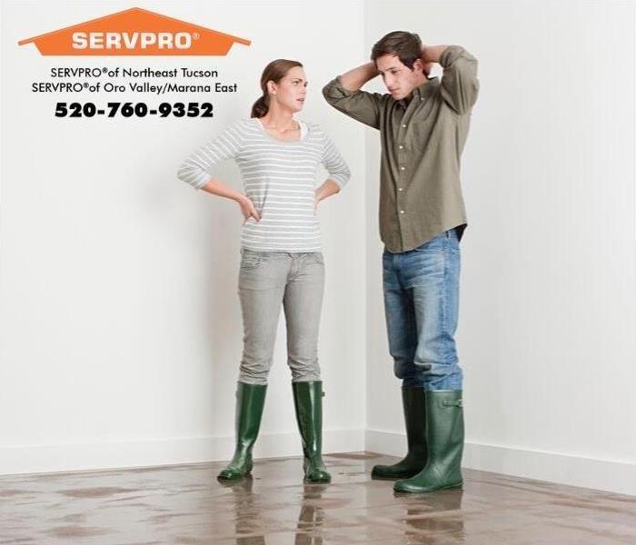 Man and woman standing on a wet floor wearing rain boots.