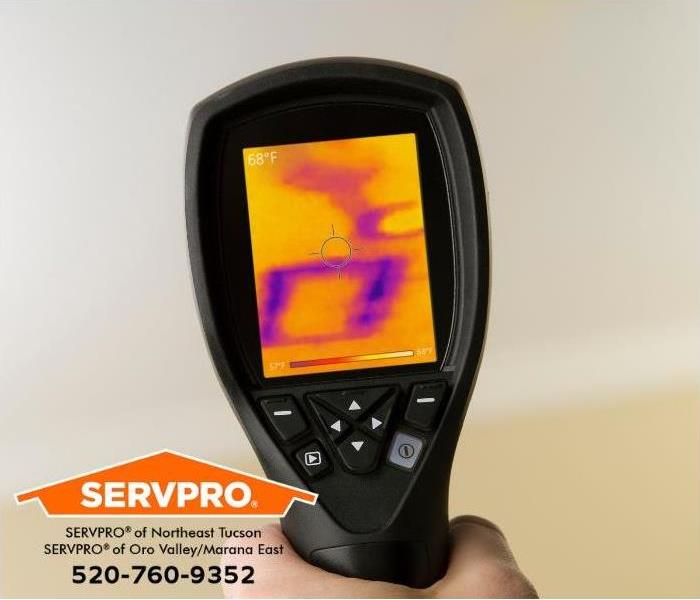 A technician uses an infrared camera to locate water damage inside a wall.